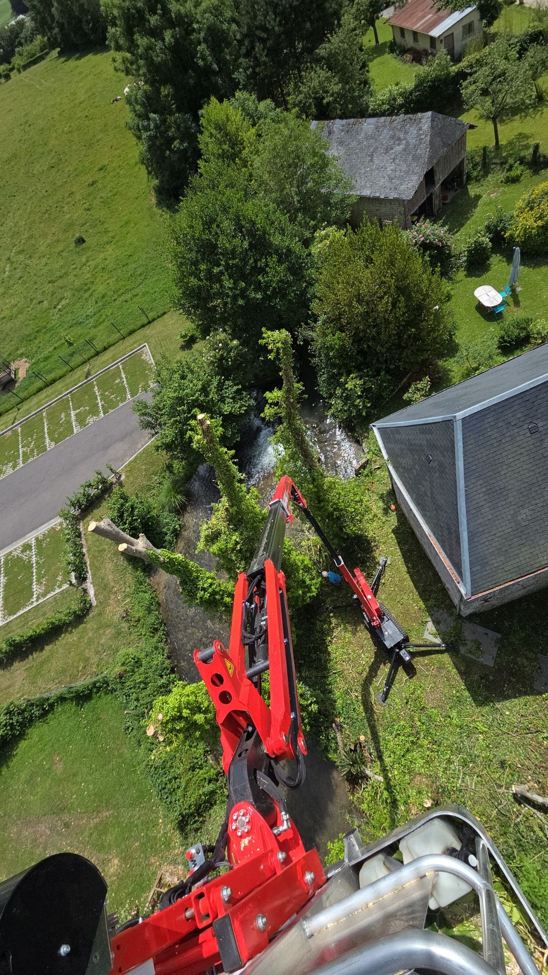 Vue depuis le panier d'une nacelle araignée déployée au-dessus d'un jardin et d'un ruisseau